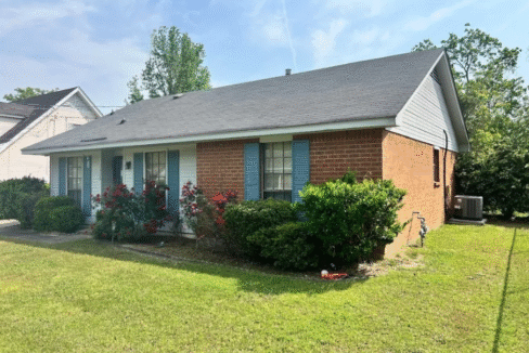 Brick house with blue shutters and garden.