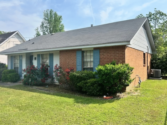 Brick house with blue shutters and garden.