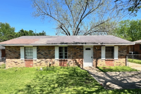 Brick house with front yard and trees.