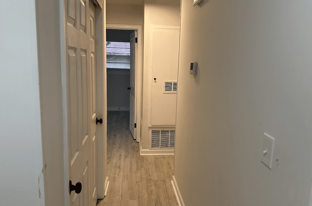 Narrow hallway with doors and wood flooring.