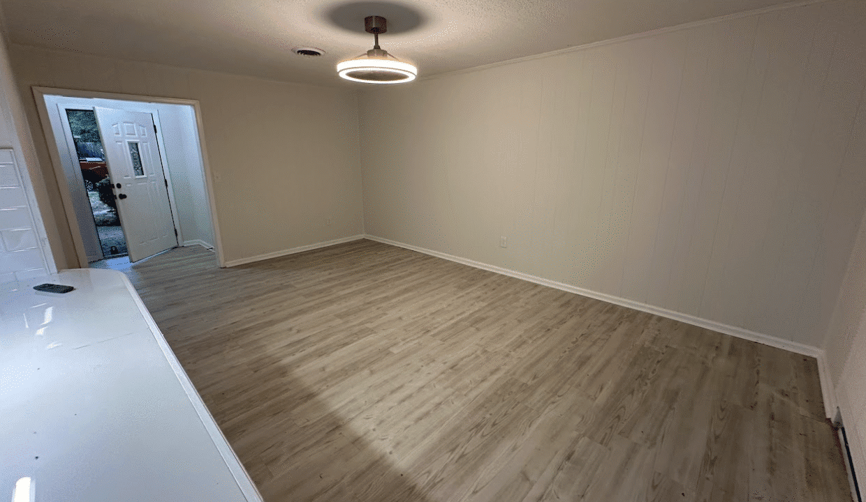 Empty room with wood flooring and light fixture.