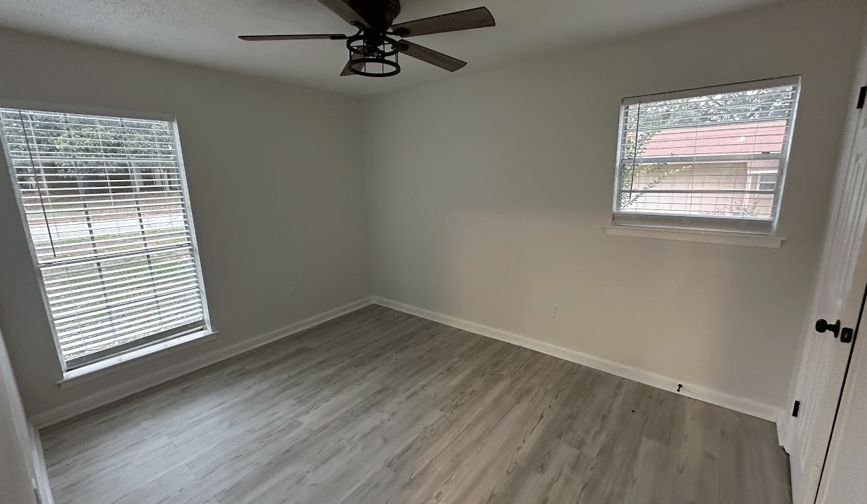 Empty room with wooden floor and windows.