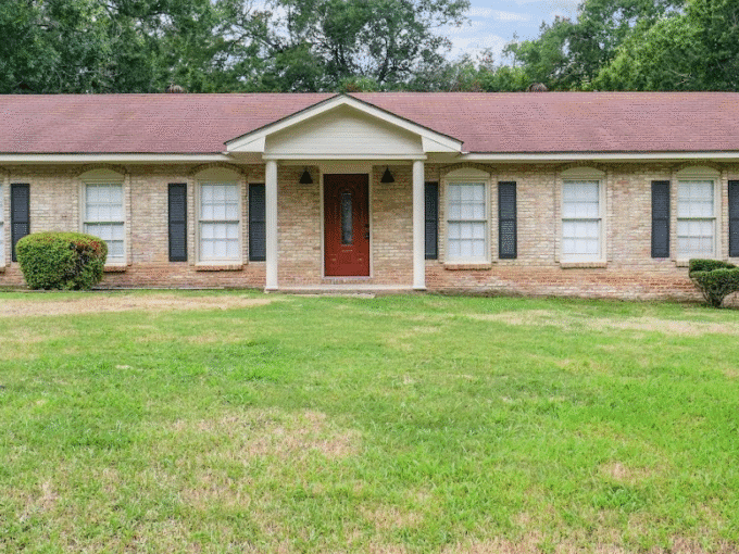 Single-story brick house with green lawn.