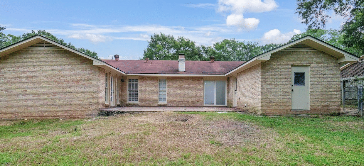 Brick house with grass yard and trees.