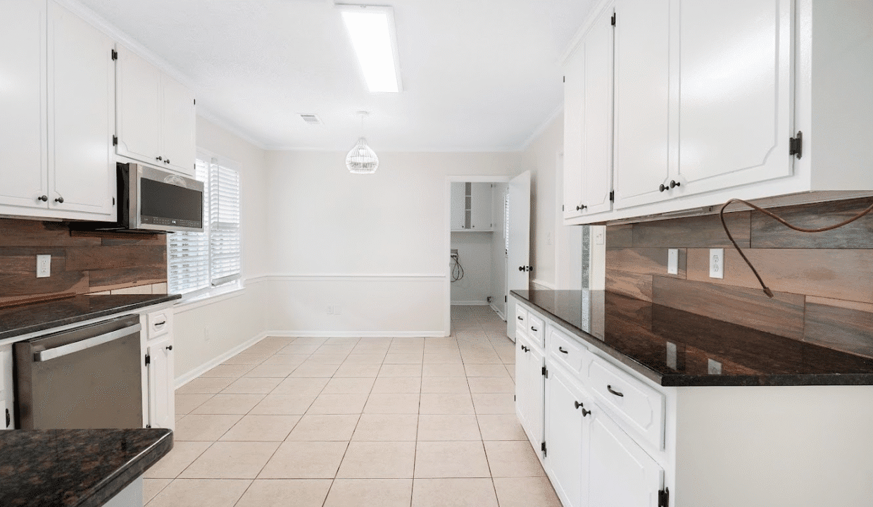 Spacious kitchen with white cabinets and tile.