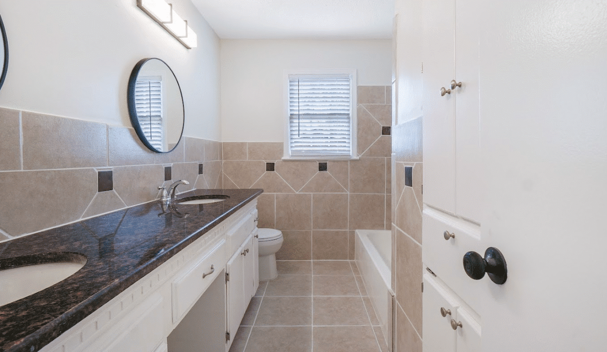 Modern bathroom with granite countertop and bathtub.
