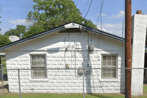 Small white house with chain-link fence.