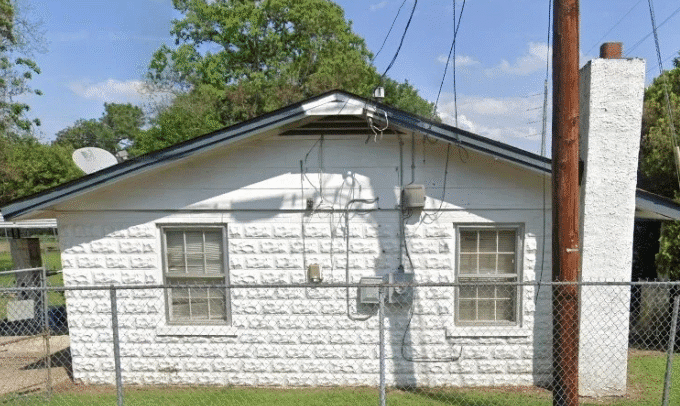 Small white house with chain-link fence.