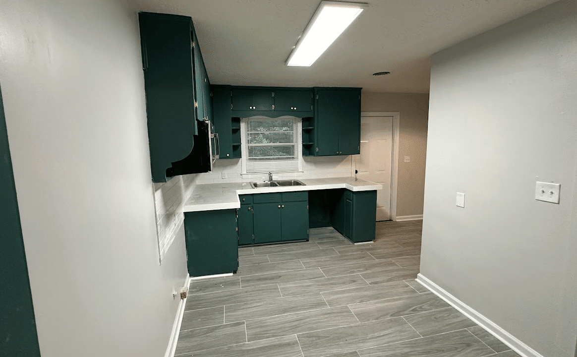 Small kitchen with green cabinets and tiles.