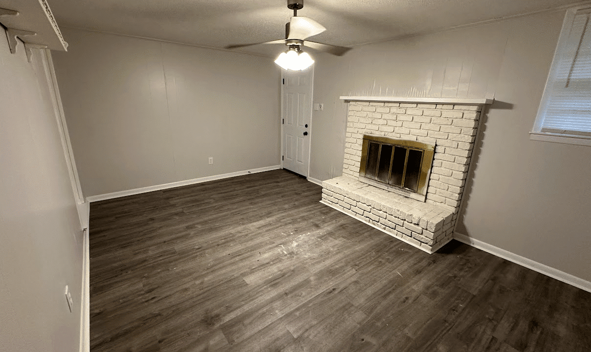 Empty room with fireplace and wooden floor.