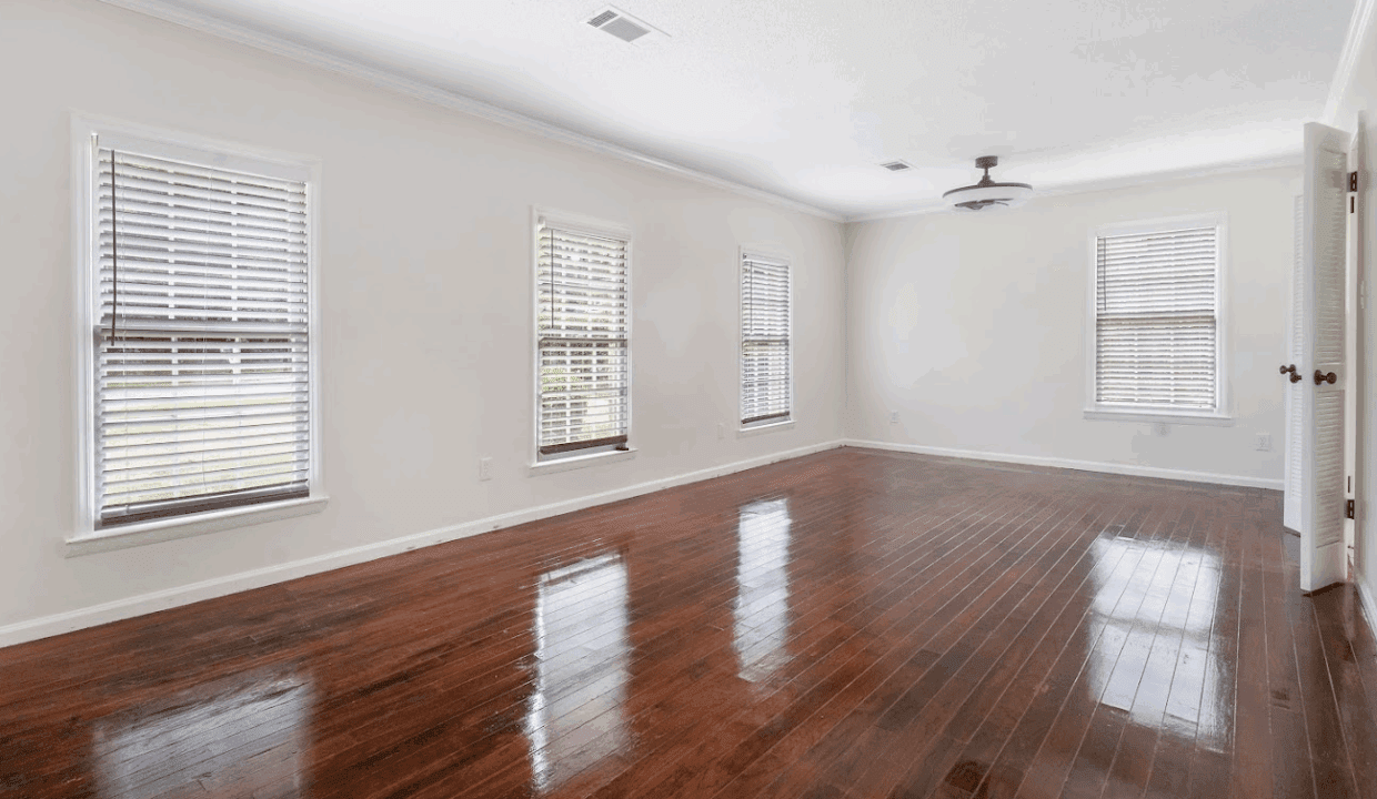 Empty room with hardwood floor and windows.