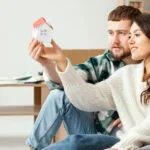 Couple holding small model house together