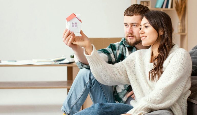 Couple holding small model house together